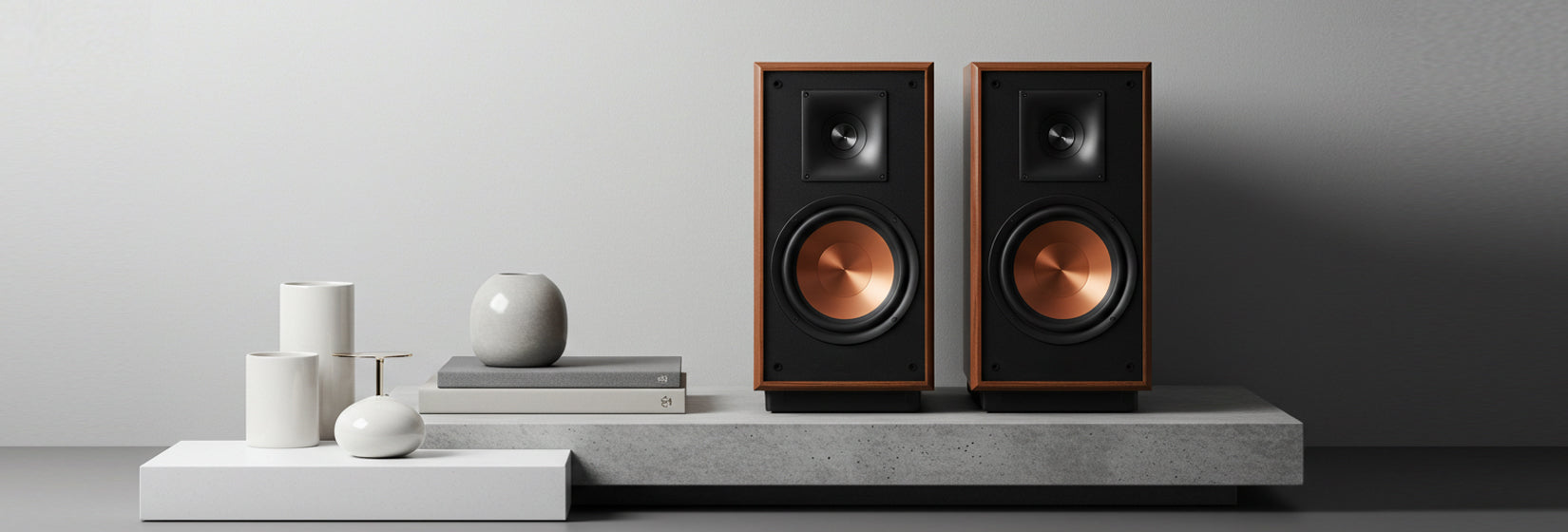 Premium bookshelf speaker pair on a clean white background with black cabinets, metallic driver accents, and luxury HiFi design.